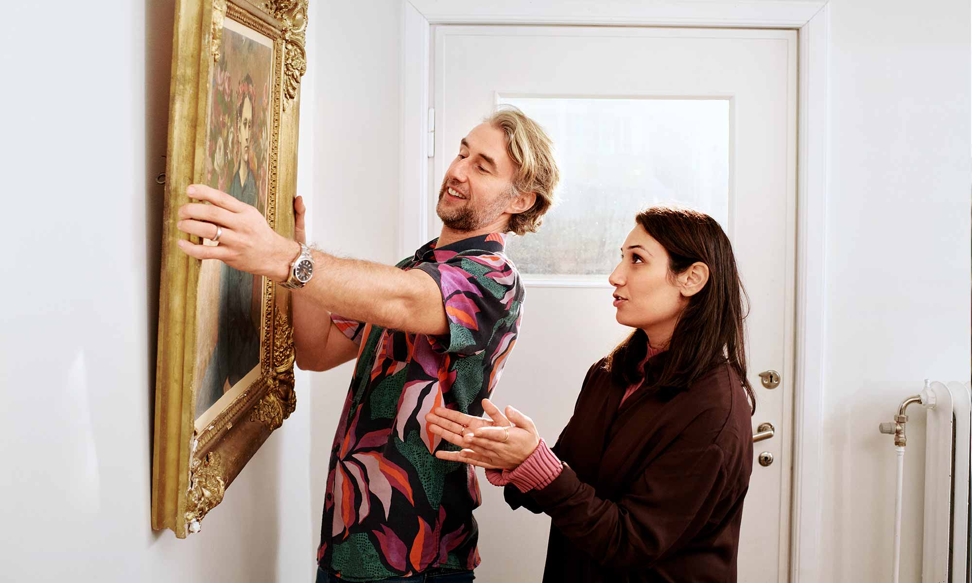 Couple hanging a painting on the wall