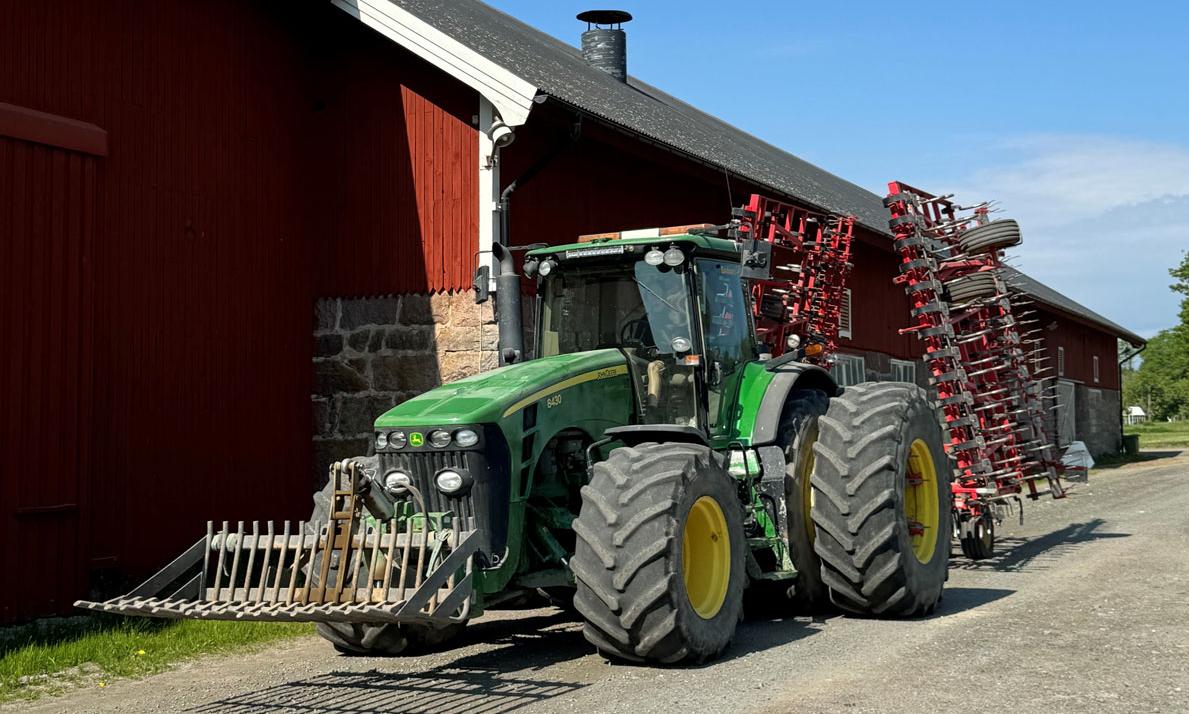 A green tractor in front of a red barn