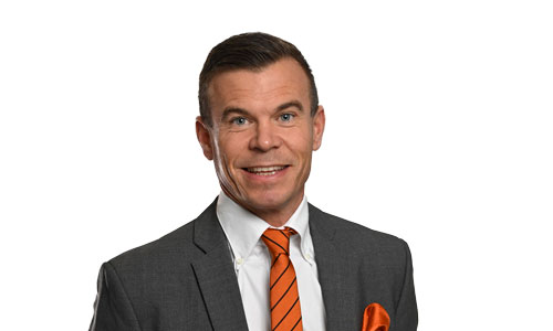 man i grå kostym, vit skjorta och orange slips