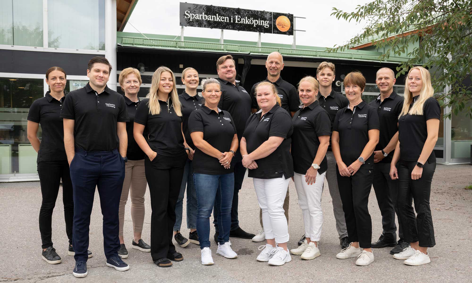 14 people standing in front of the entrance to Sparbanken i Enköping