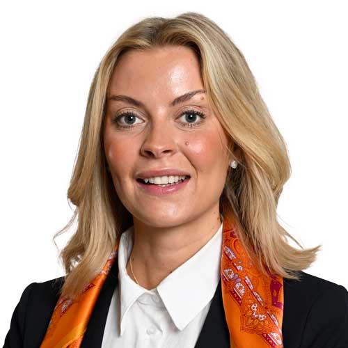 a women with blond hair, white shirt, black jacket and an oranges scarfe